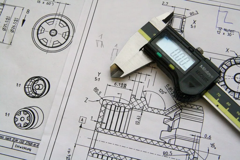 Compasso eletrônico em cima de esquemas de engenharia mecânica impressos