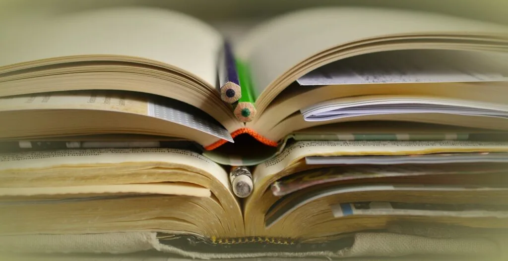 Uma grande pilha de livros acadêmicos focados em TCC Engenharia, cobrindo temas variados de Engenharia de Produção, Mecânica e Elétrica. A imagem representa o esforço e a dedicação necessários para a pesquisa e escrita de um trabalho final de conclusão de curso.