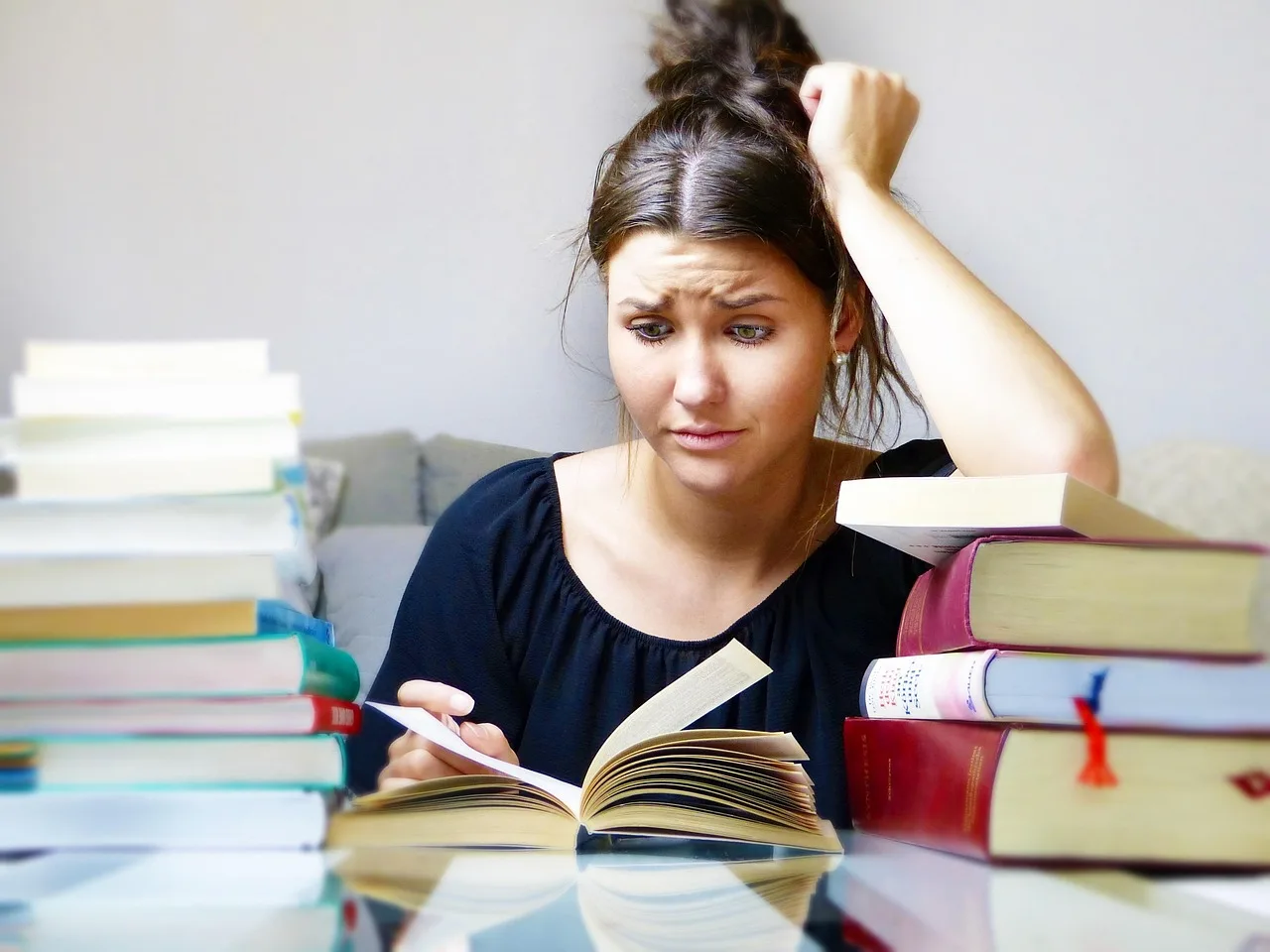 Estudante de engenharia cercada por uma pilha de livros, se preparando para o TCC Engenharia, com foco em temas de Engenharia de Produção, Mecânica e Elétrica.