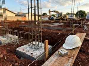 Tipos de fundação: sapata de concreto com arranque de pilar em canteiro de obra, com capacete e trena